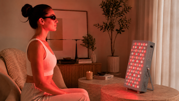 Woman using a red light therapy panel correctly at home